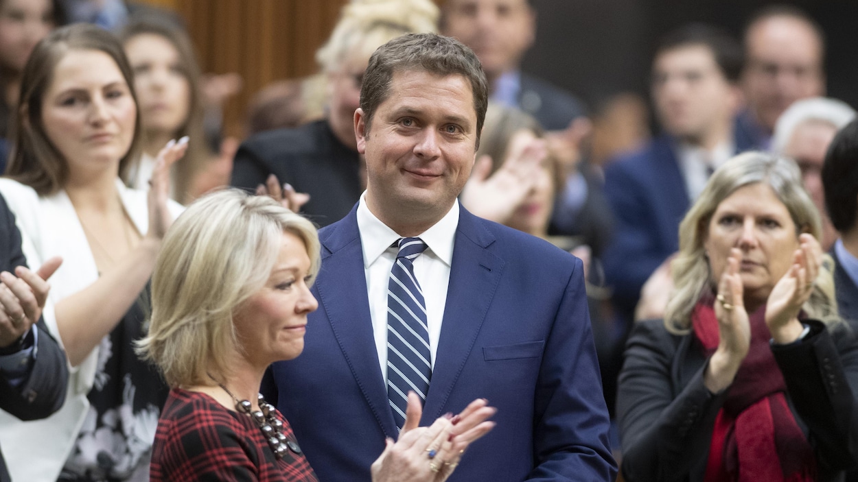 Andrew Scheer, qui regarde la caméra, affiche un demi-sourire.
