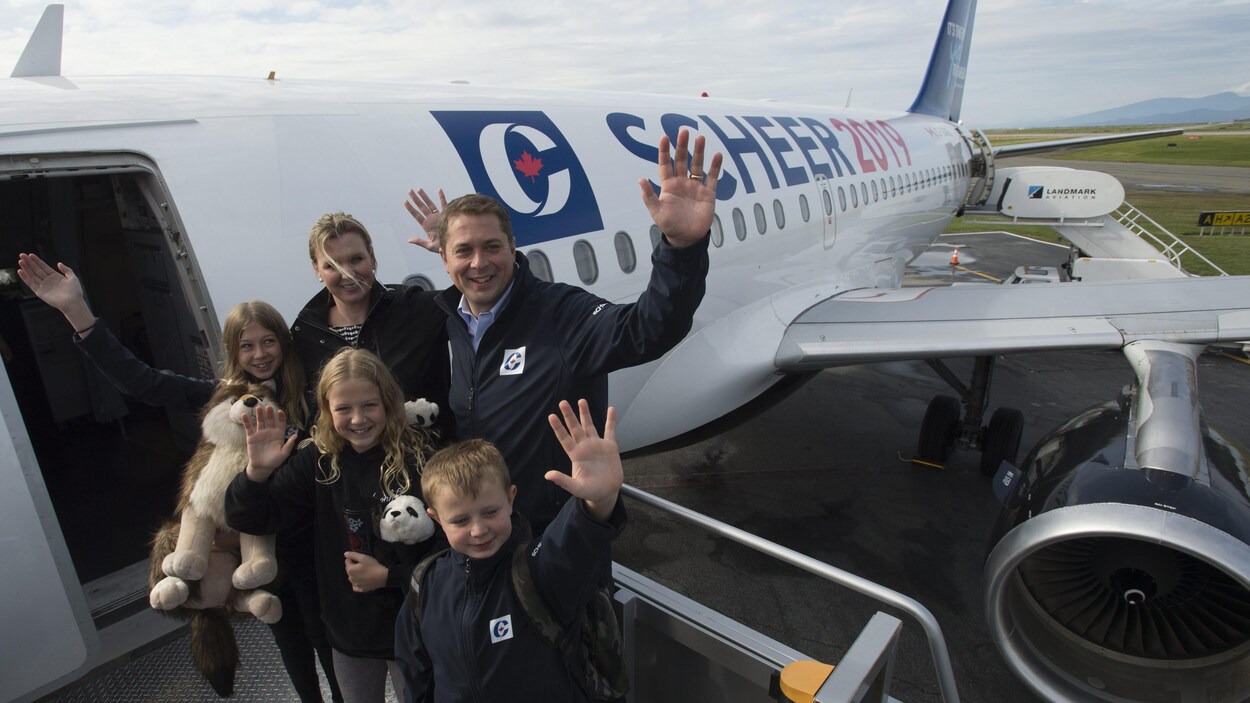 Andrew Scheer, sa femme et ses trois enfants font des salutations avant d'entrer dans l'avion de campagne.