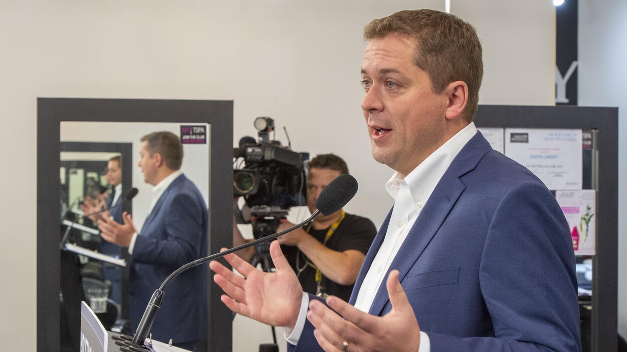 M. Scheer prend la parole derrière un lutrin.