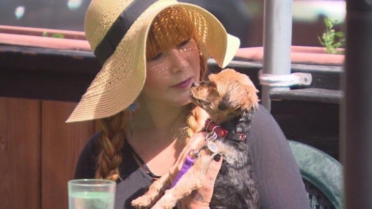 Courtney Ware est assise à une table sur la terrasse du restaurant Saffron's et tient sa chienne Coco dans les bras.