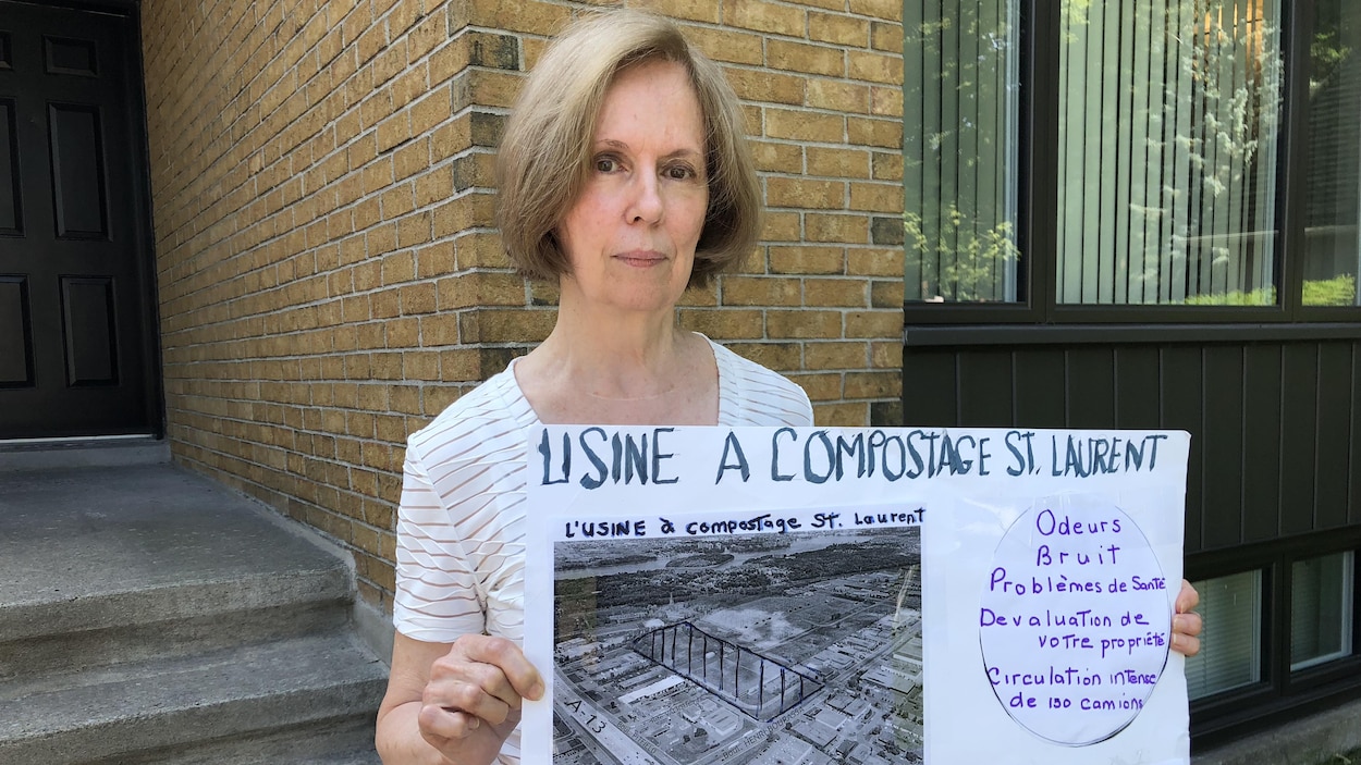 Anne Klein, devant sa maison, tient une affiche qui décrit les risques qu'elle associe au futur centre de compostage