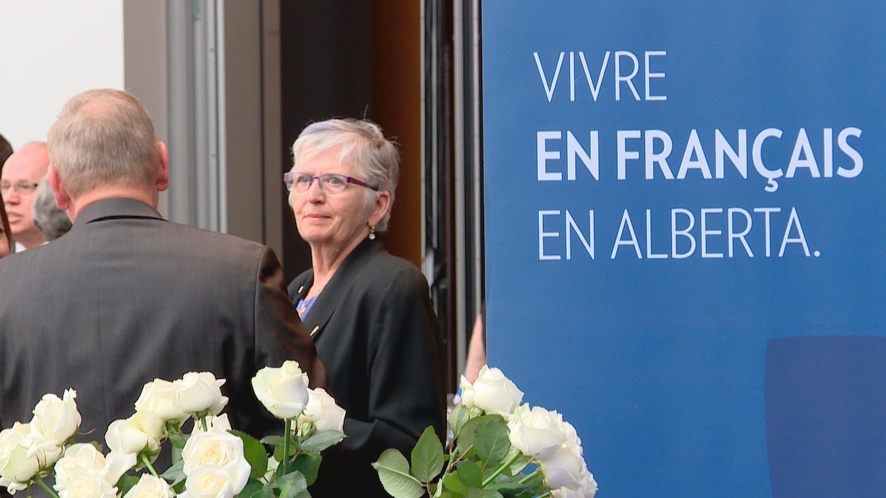 Une bannière où se lit «Vivre en français en Alberta», à droite, avec la députée Annie McKitrick qui écoute un interlocuteur, vu de dos, avec des roses blanches au bas de l'image. Une bannière où se lit «Vivre en français en Alberta», à droite, avec la députée Annie McKitrick qui écoute un interlocuteur, vu de dos, avec des roses blanches au bas de l'image.