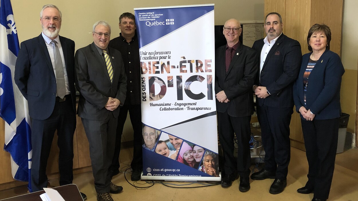 Des dignitaires posent autour d'une affiche du CISSS-AT.