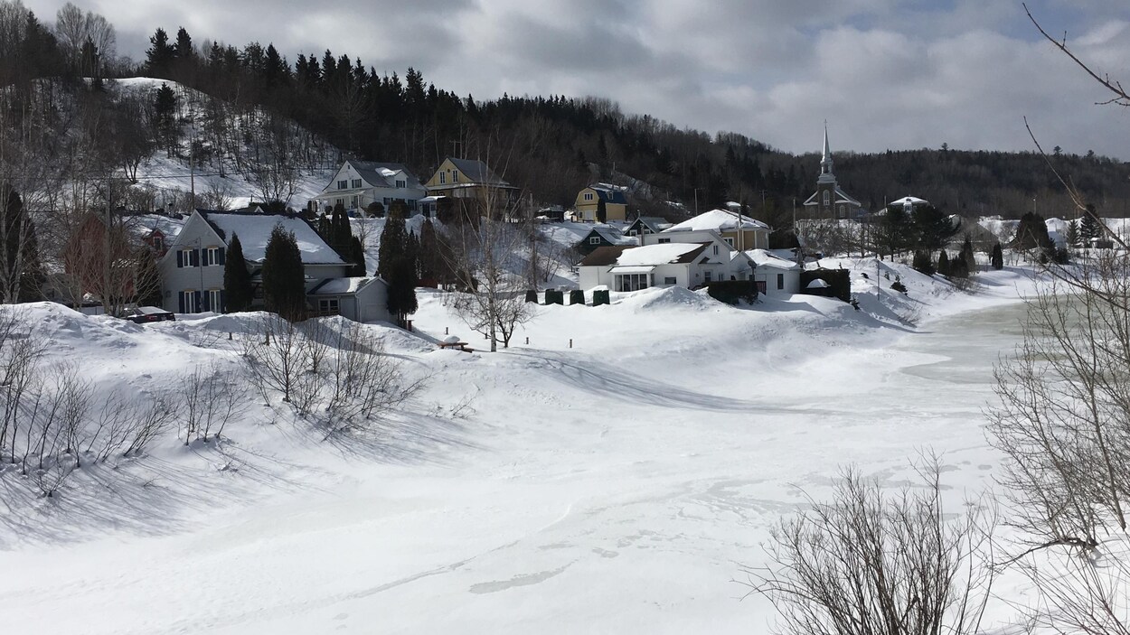 Les maisons et l'église sous la neige près de la rivière
