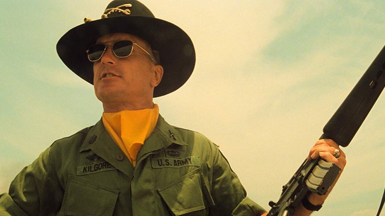 Un militaire américain porte un chapeau et tient une arme.