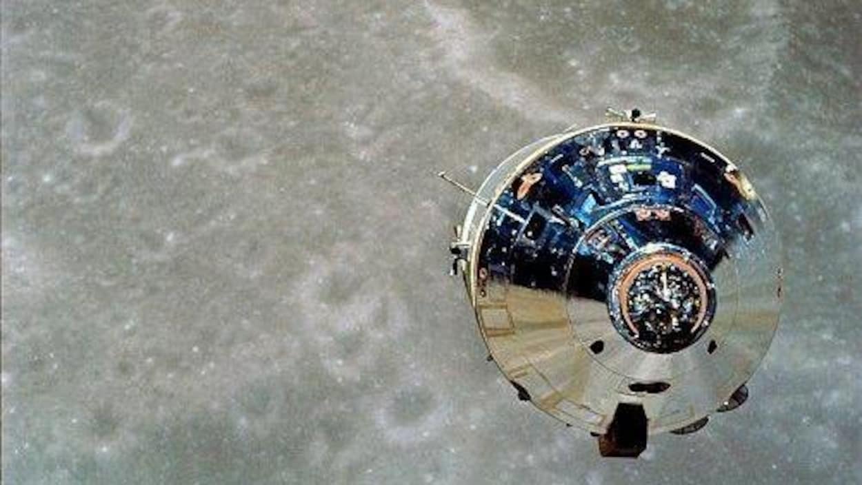 Un objet métallique flotte dans l'espace, en direction de la surface de la lune.
