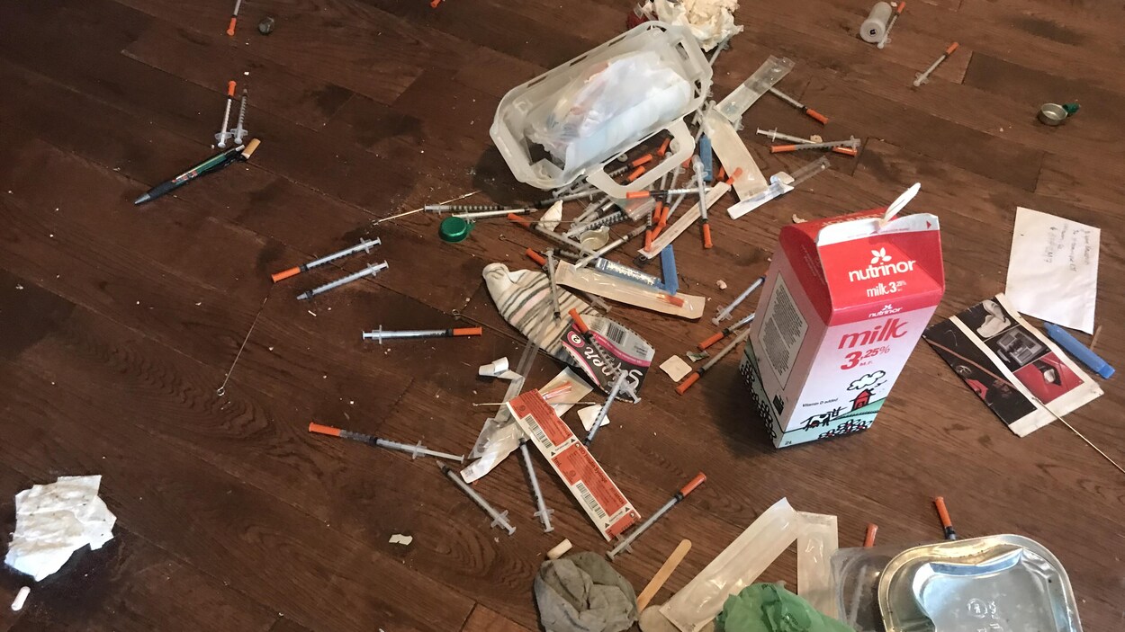 Des dizaines de seringues utilisées sont sur le plancher.
