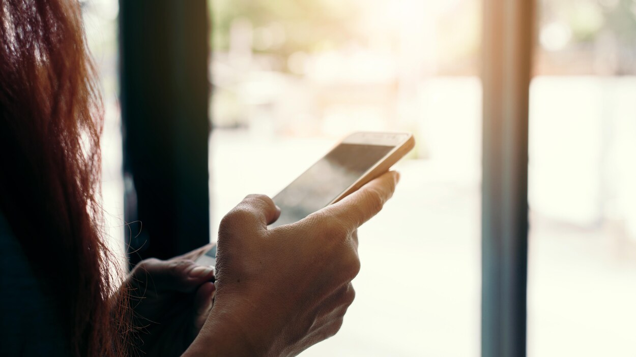 Une femme consulte son téléphone cellulaire.