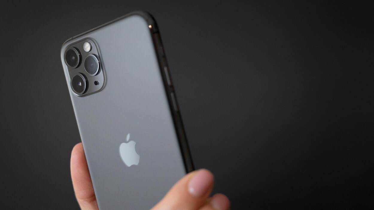 Une personne tient un téléphone iPhone 1 Pro.