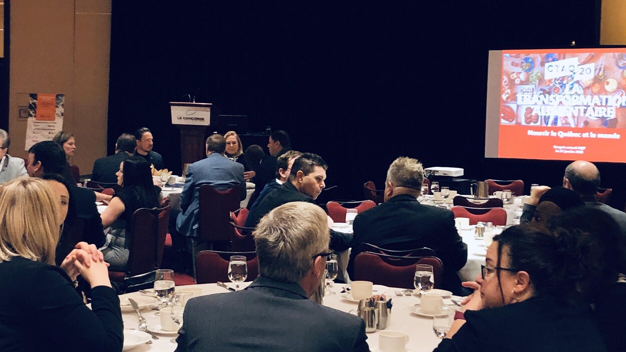 Des gens assis autour de tables rondes dans une salle de conférence