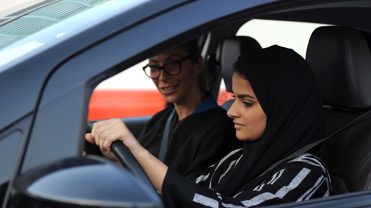 Une femme portant un voile noir est au volant d'une voiture accompagnée d'une autre femme portant des lunettes.