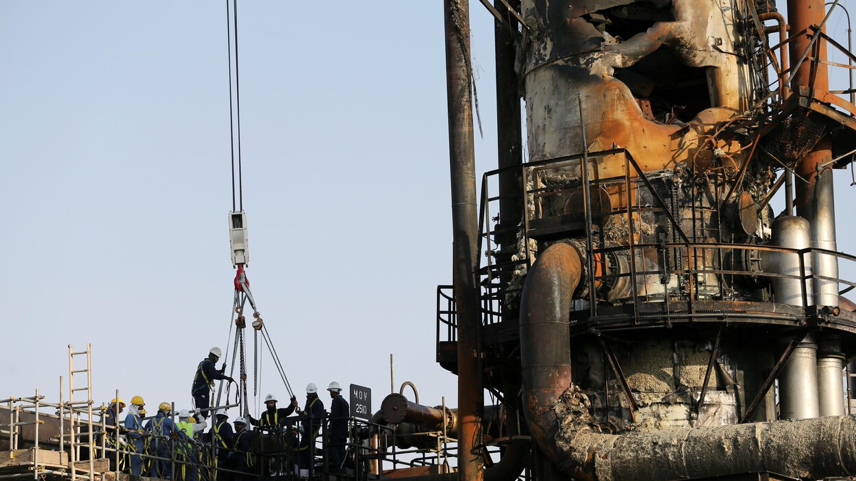 Des travailleurs montent dans une nacelle au site pétrolier de Saudi Arama, endommagé à la suite de l'attaque.