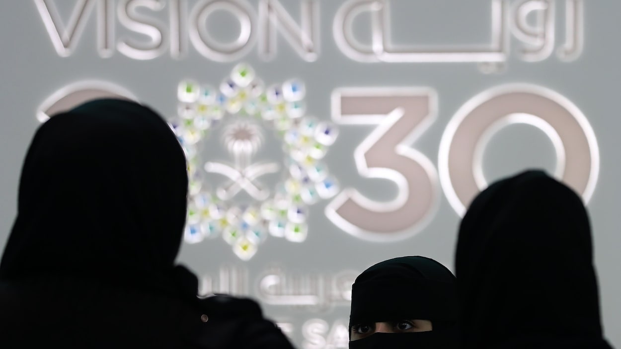 Des silhouettes de femmes voilées devant le logo de « Vision 2030 ».