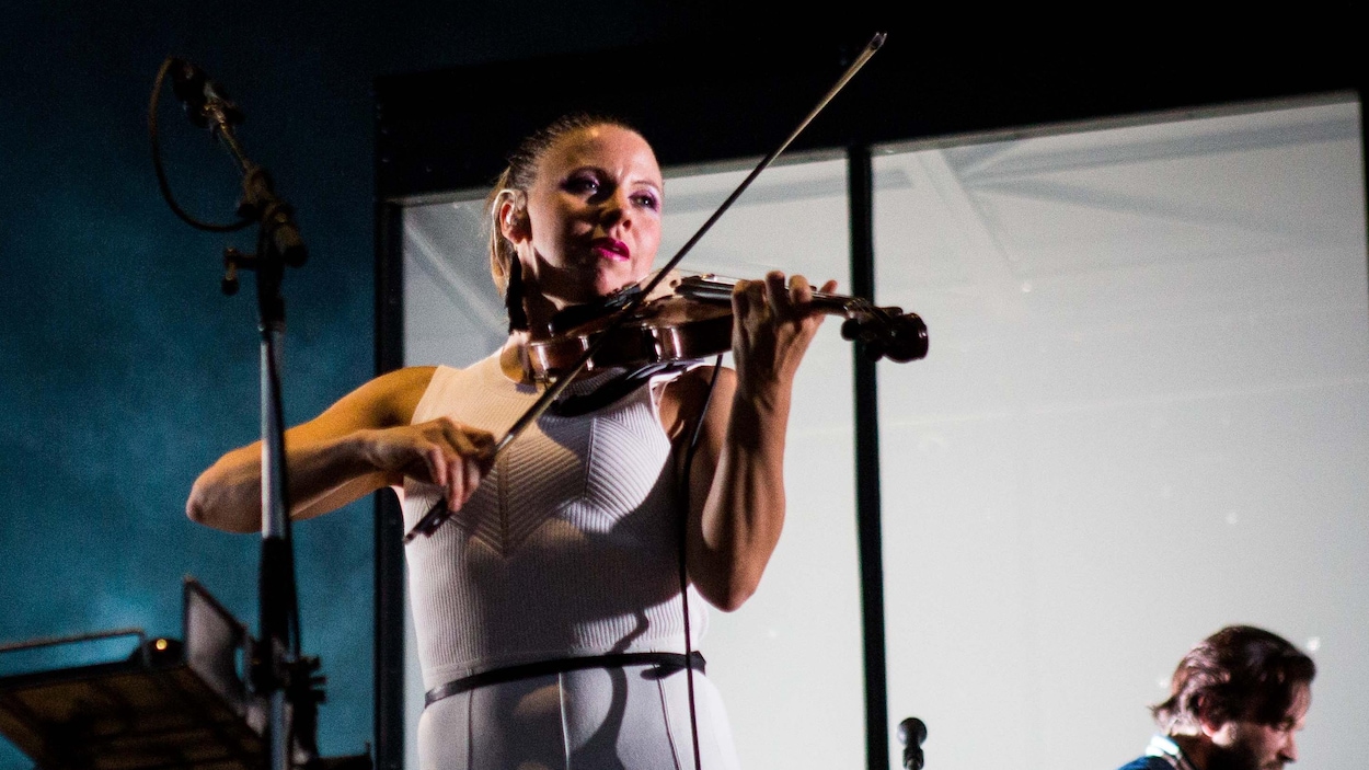 La violoniste du groupe Arcade Fire, Sarah Neufeld, jouant de son instrument sur scène lors d'un spectacle.