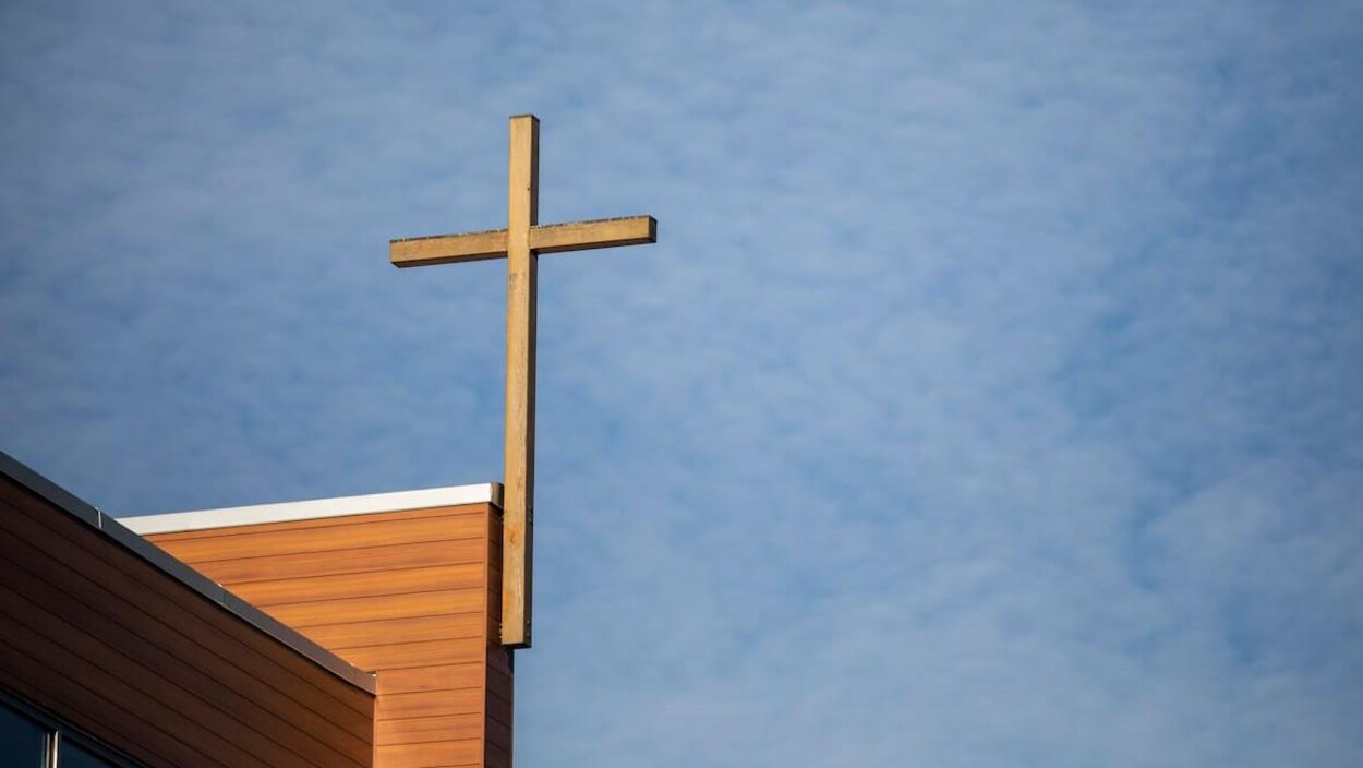 Une croix accrochée à la structure d'un bâtiment.