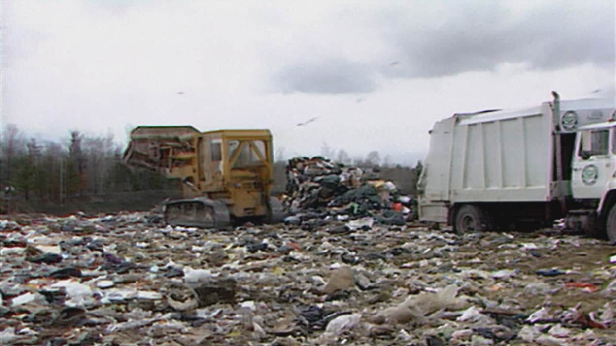 Un camion et une pelle mécanique sont à l'oeuvre dans sur un site d'enfouissement des déchets.