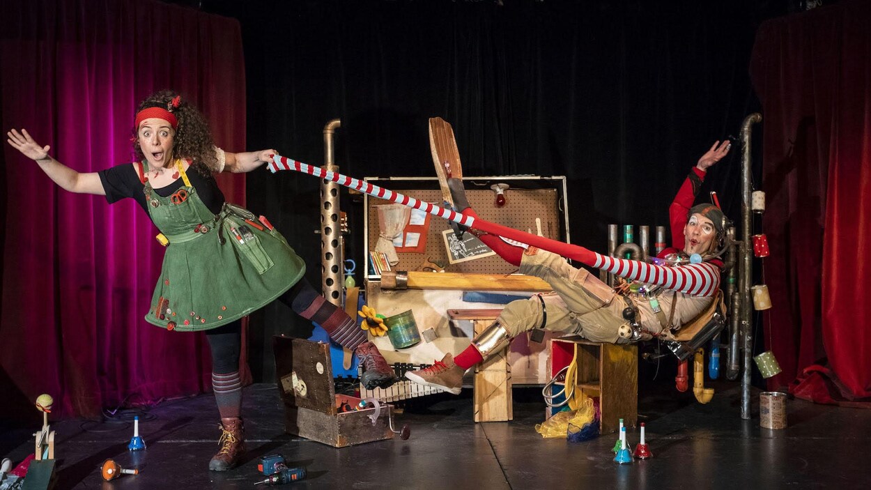 Scène humoristique lors d'un spectacle pour enfants. Une femme en costume tire sur la manche à rallonge d'un homme, lui aussi en costume.