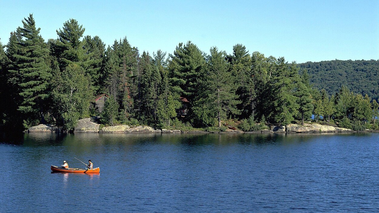 Deux hommes à la pêche dans un canot sur un lac.