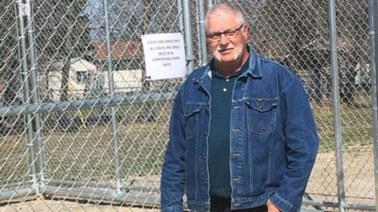 Un homme est debout à côté d'une grande cage.