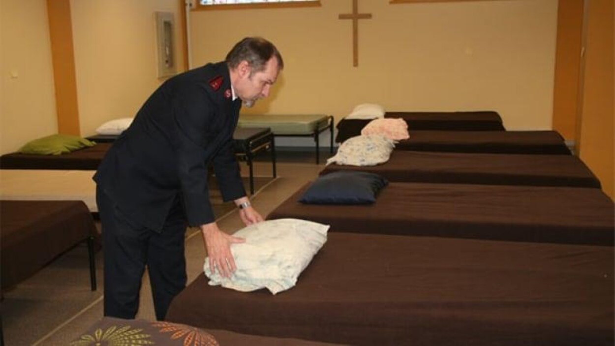 Un homme préparant des lits dans un refuge.
