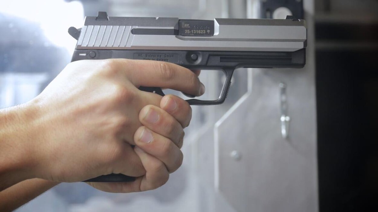 Un gros plan sur une main qui tient une arme à feu.