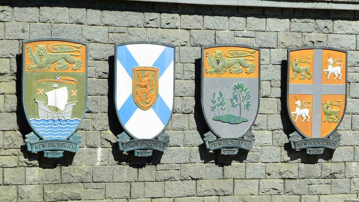 Les armoiries des quatre provinces fixées à un mur de brique.
