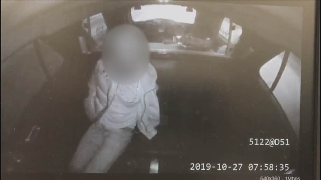 Un homme au visage flouté assis dans un véhicule.