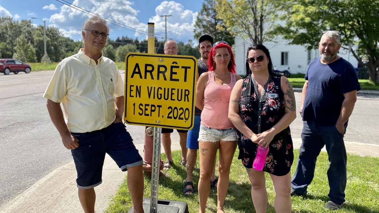 Le conseiller Michel Thiffault et des citoyens devant une affiche sur laquelle il est écrit "arrêt en vigueur 1er septembre 2020".