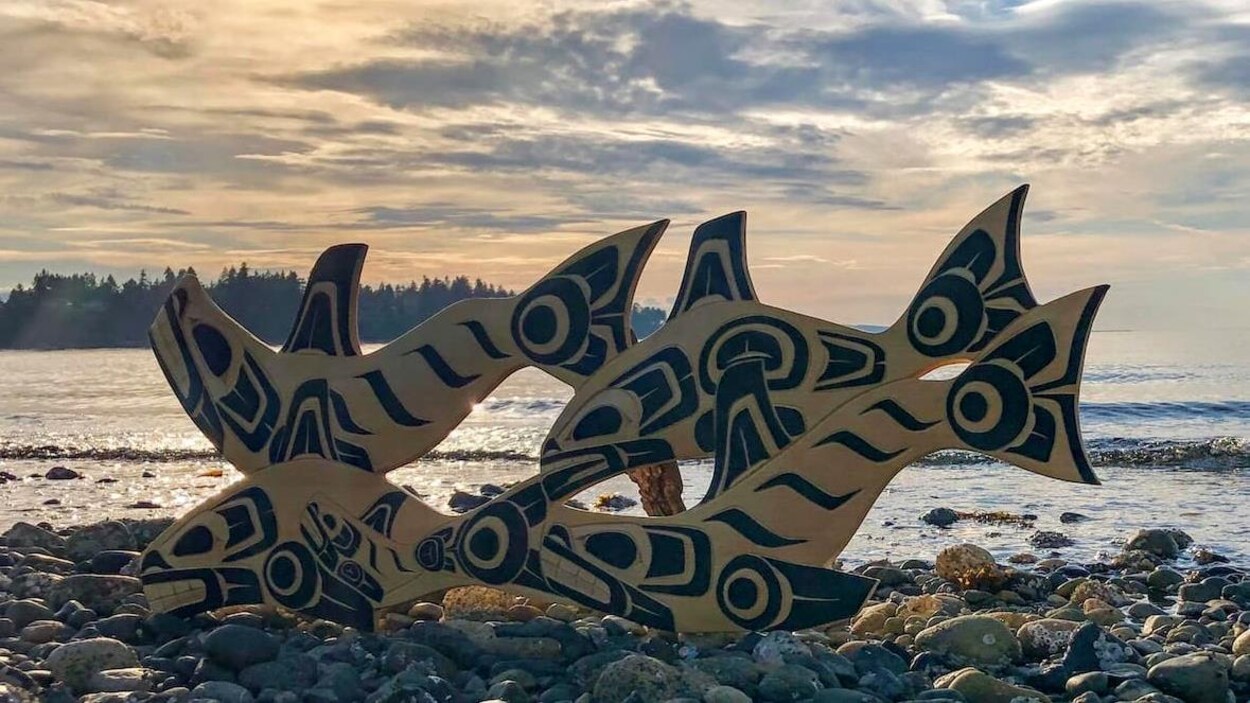 Une oeuvre d'art au bord de la mer montre des poissons sculptés dans le bois et peints en bleu marine.