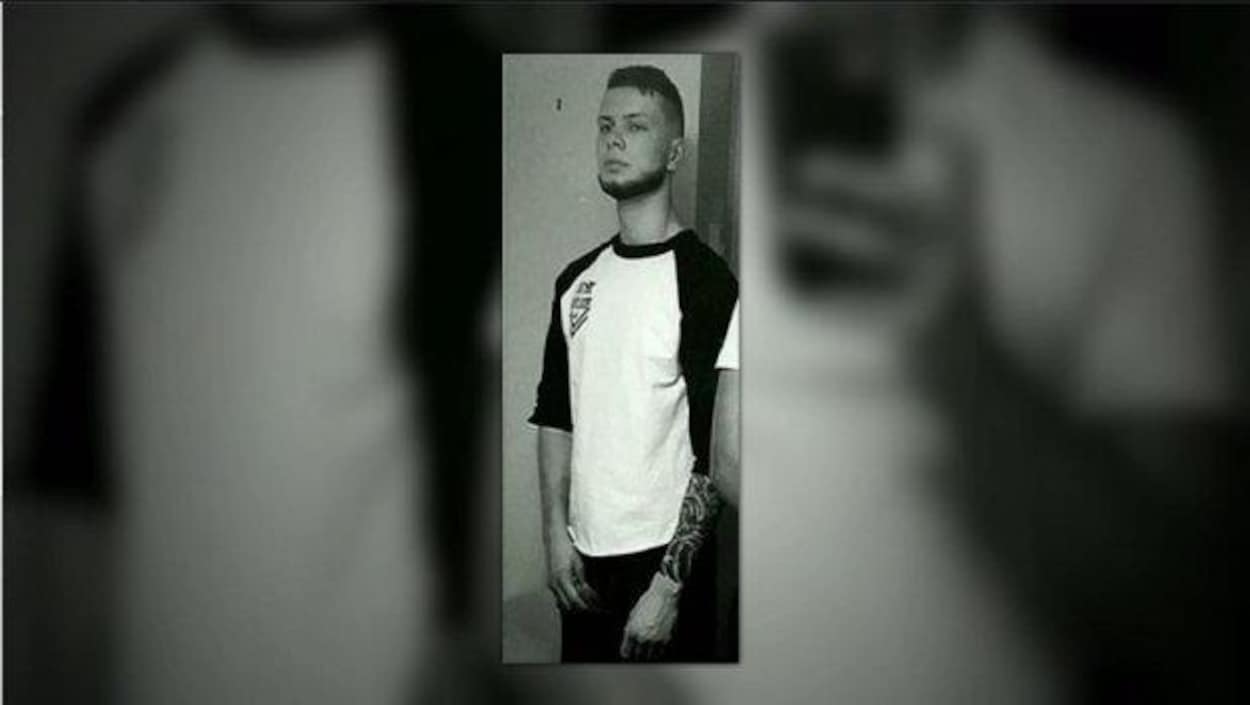 Jeune homme qui ne sourit pas avec un tatouage sur le bras.