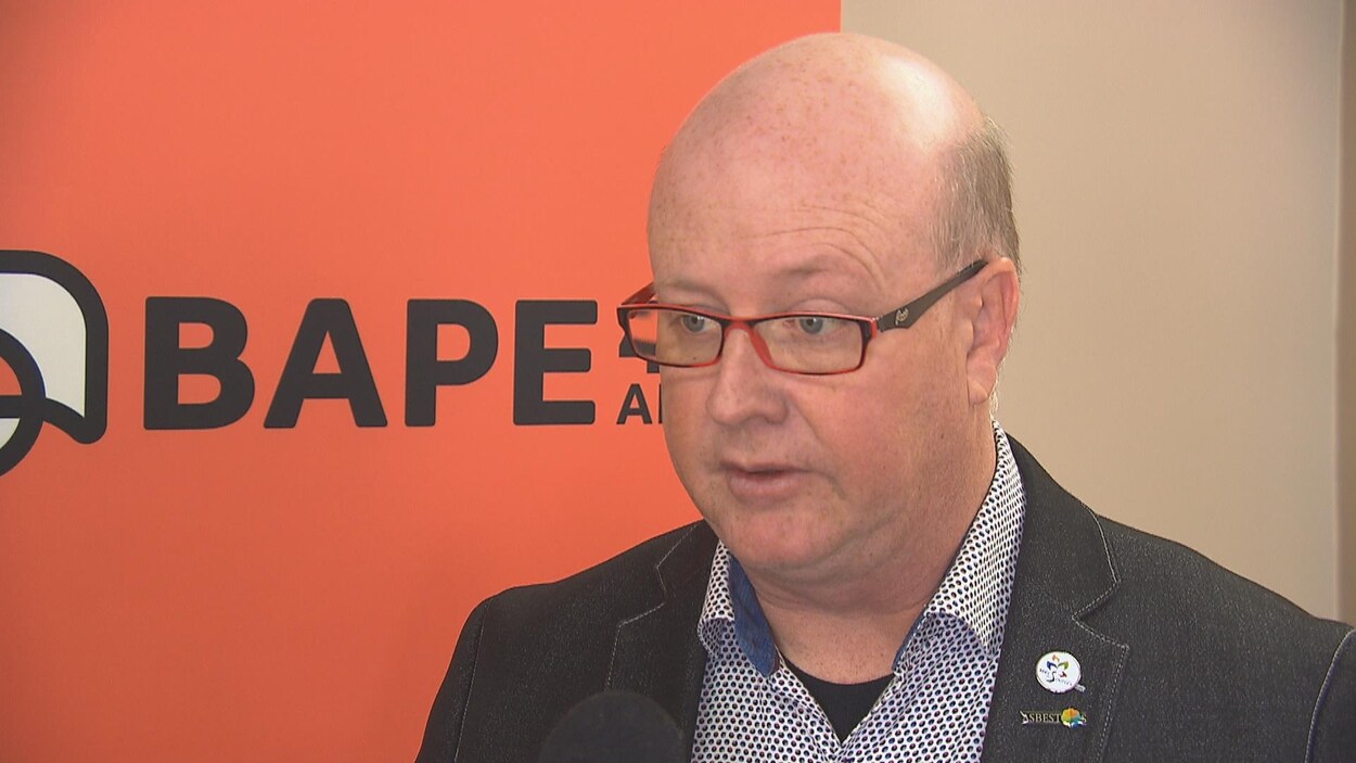 Hugues Grimard, maire d'Asbestos devant une pancarte du BAPE.