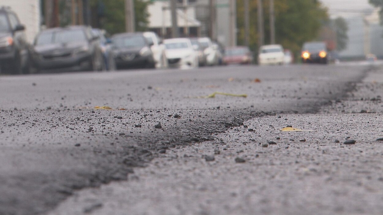 Des véhicules sont stationnés le long d'une rue asphaltée.