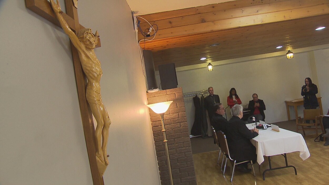 Un crucifix est accroché près de la table de conférence.