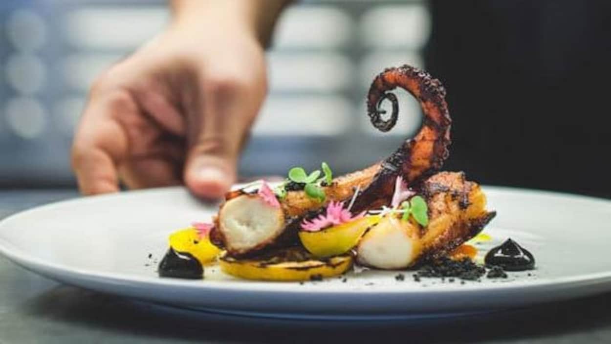 Un chef met la touche finale à un plat du restaurant Le poivre noir