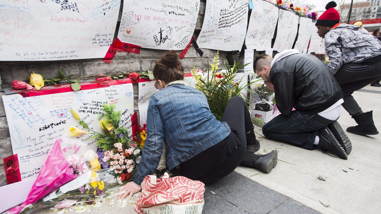 Des gens lisent les messages laissés au mémorial dans un parc du nord de Toronto.