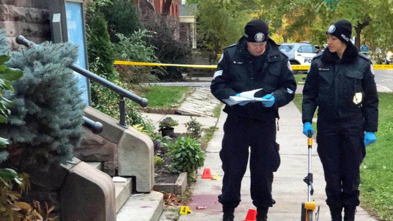Deux policiers sur le trottoir près de cônes marquant des indices.