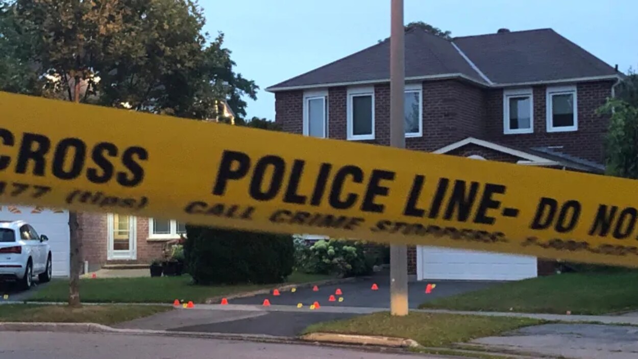 Une banderole de police jaune devant une maison en briques à deux étages.