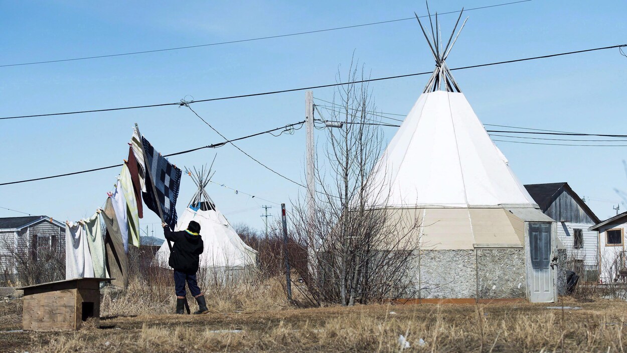 Une femme étend du linge près d'un tipi.