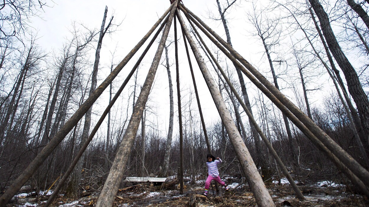 Une petite fille joue dans un tipi dans la forêt près d'Attawapiskat.