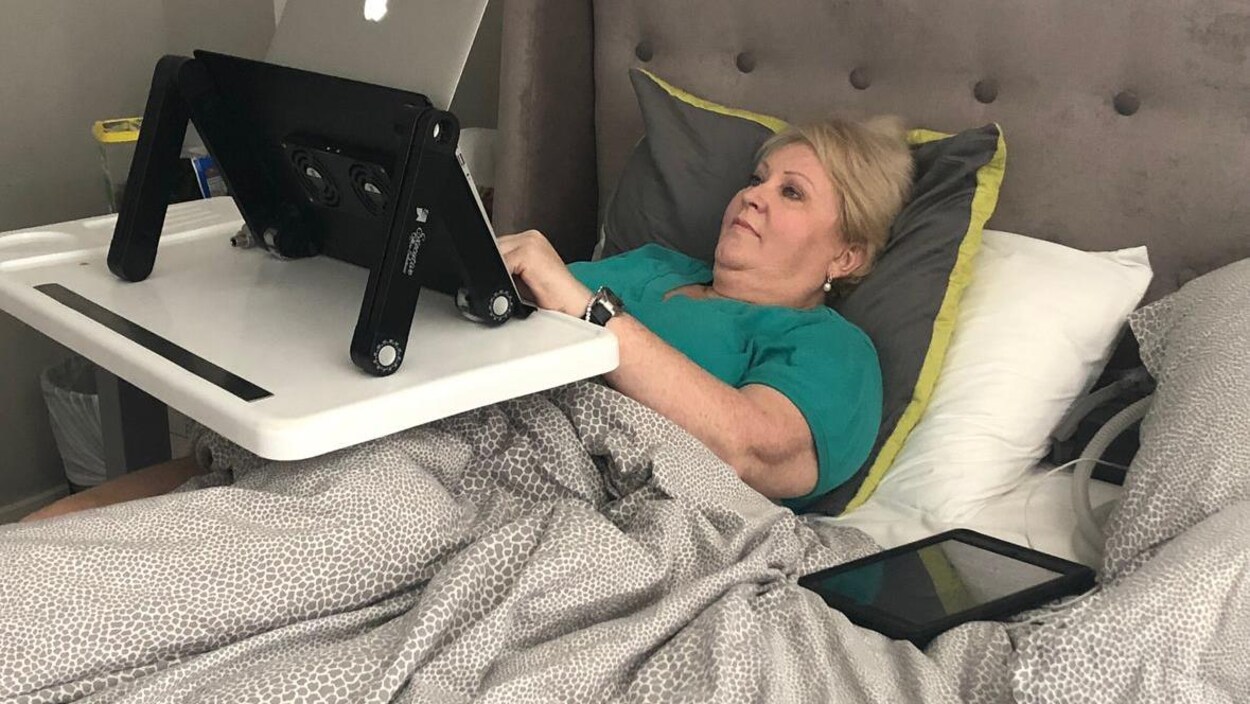 Audrey Parker lit sur un ordinateur, couchée dans son lit.