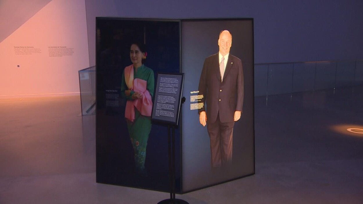 Un panneau dans une exposition portant l'image d'une femme asiatique sur son côté gauche est assombri tandis que le portrait d'un homme sur le côté droit est illuminé.