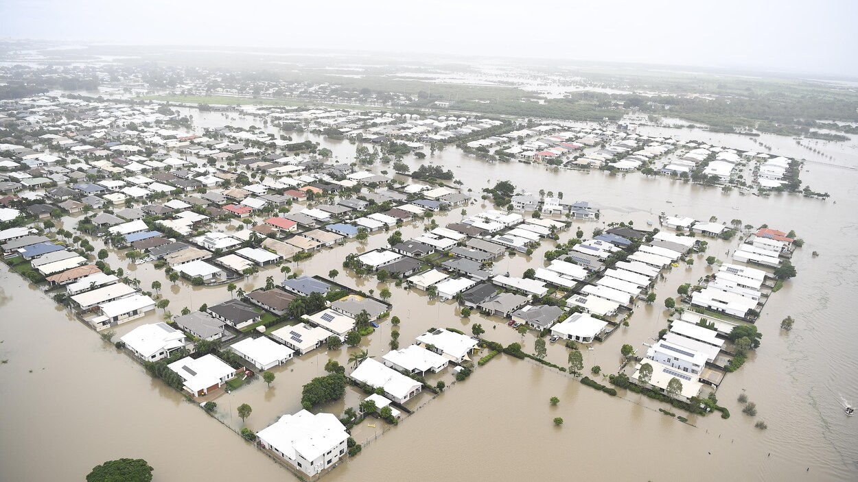 Vue aérienne d'un quartier résidentiel sous les eaux brunâtres en Australie.