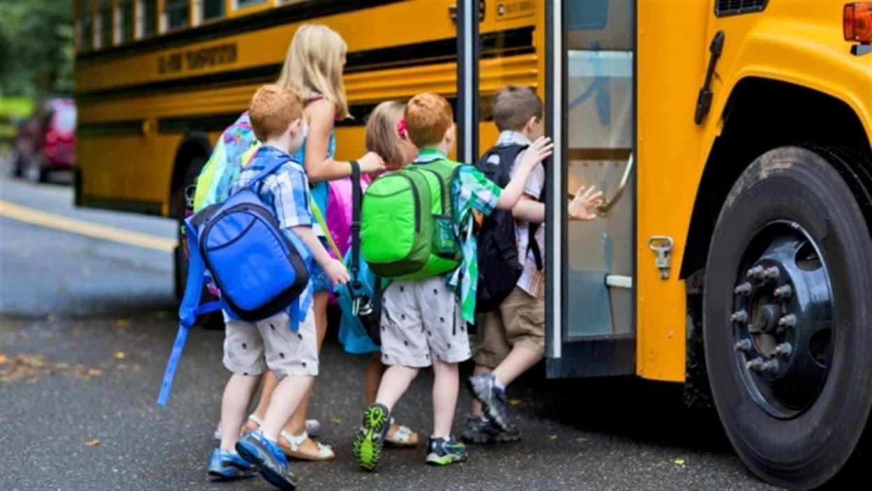 Des enfants avec des sacs à dos montent dans un bus Des enfants avec des sacs à dos montent dans un bus