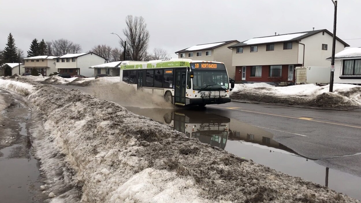 Une autobus roulant dans une flaque d'eau.