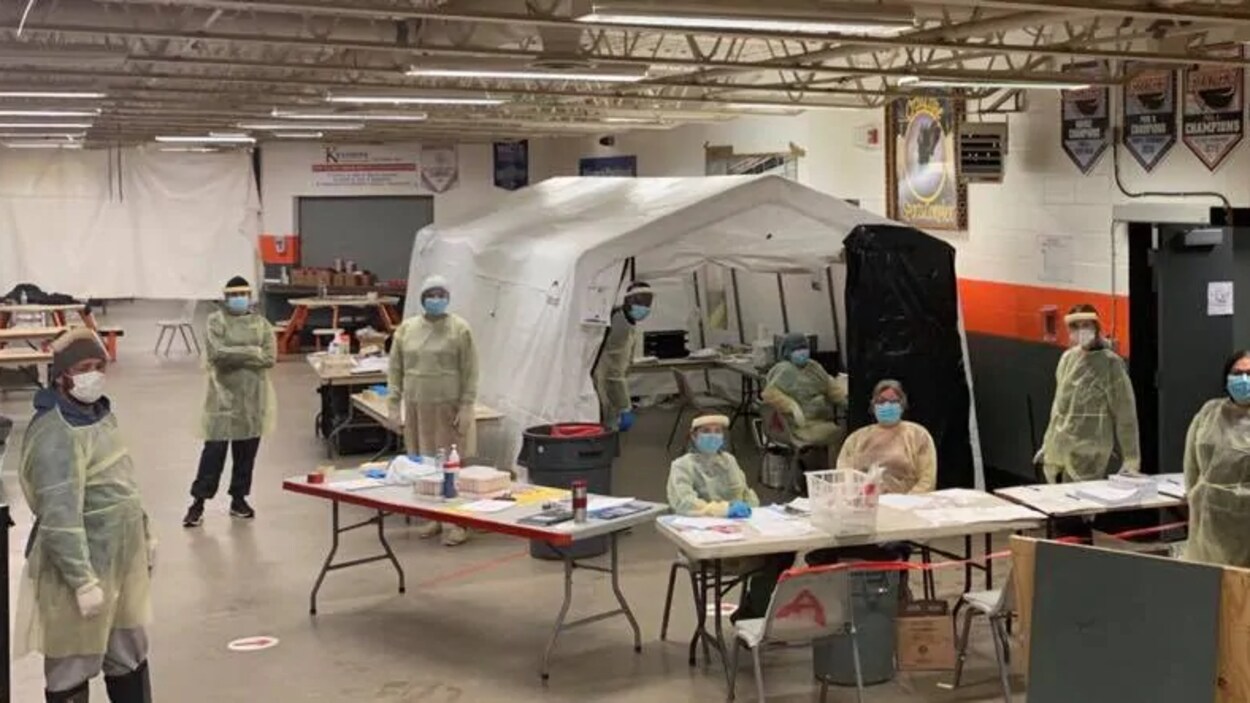 Plusieurs infirmières portent des masques et sont à l'intérieur d'un espace permettant de tester la communauté contre la COVID-19.