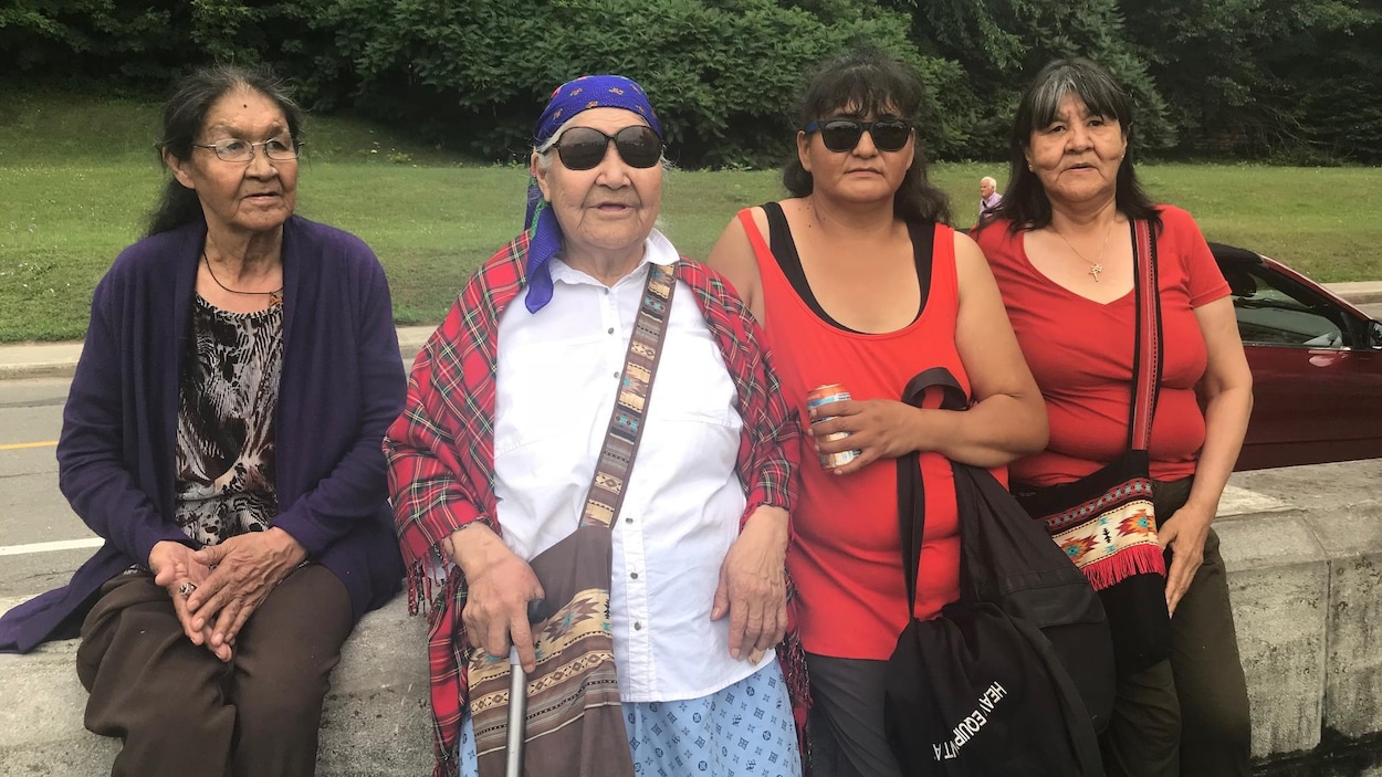 Quatre femmes autochtones sont assises sur un muret près de la basilique de Sainte-Anne-de-Beaupré.