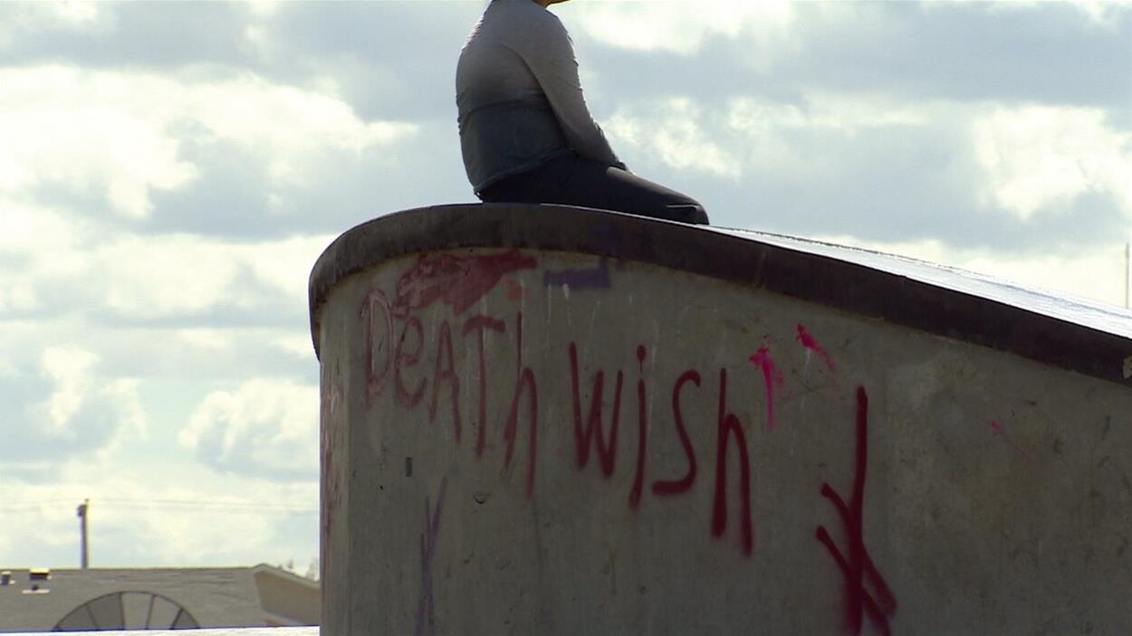 Un jeune est assis sur une structure en ciment.