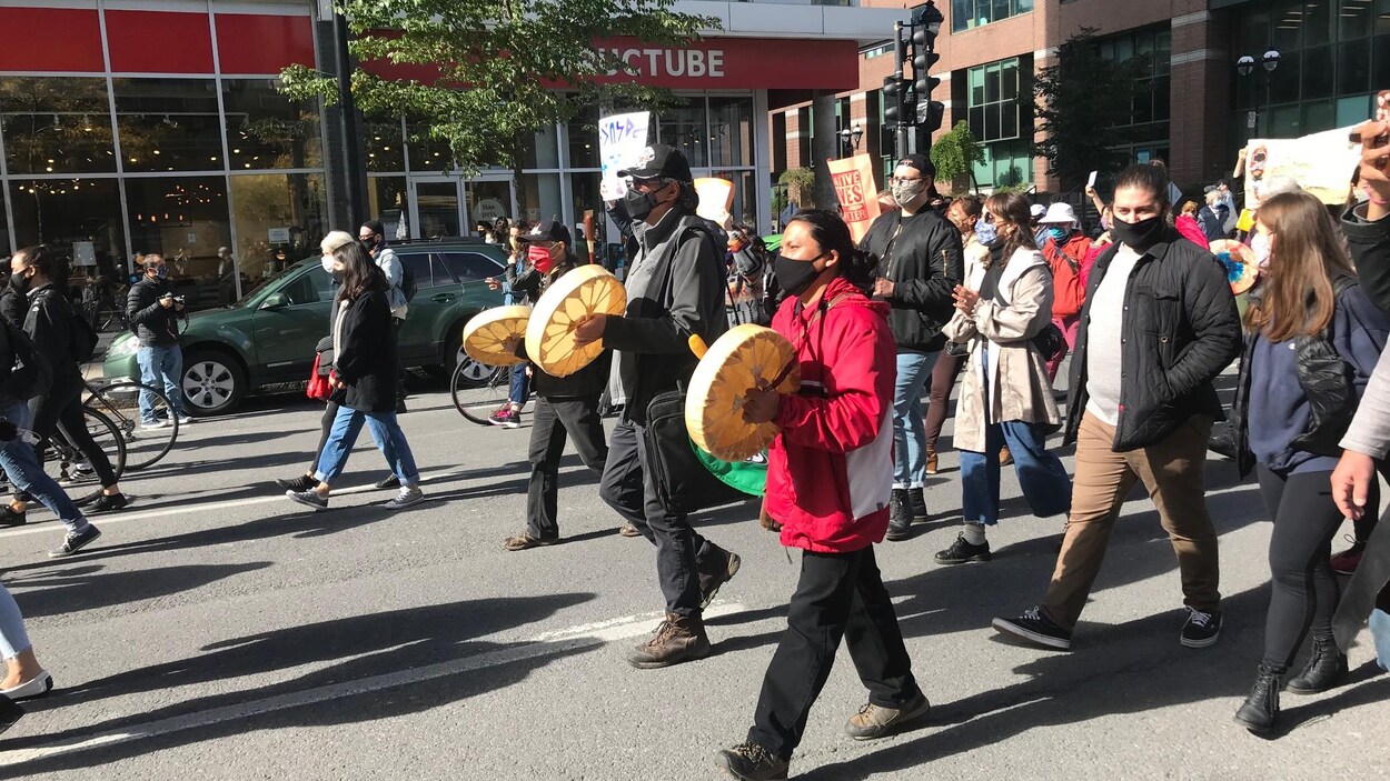 Des Autochtones jouent du tambour en marchant le long du boulevard René-Lévesque à Montréal.
