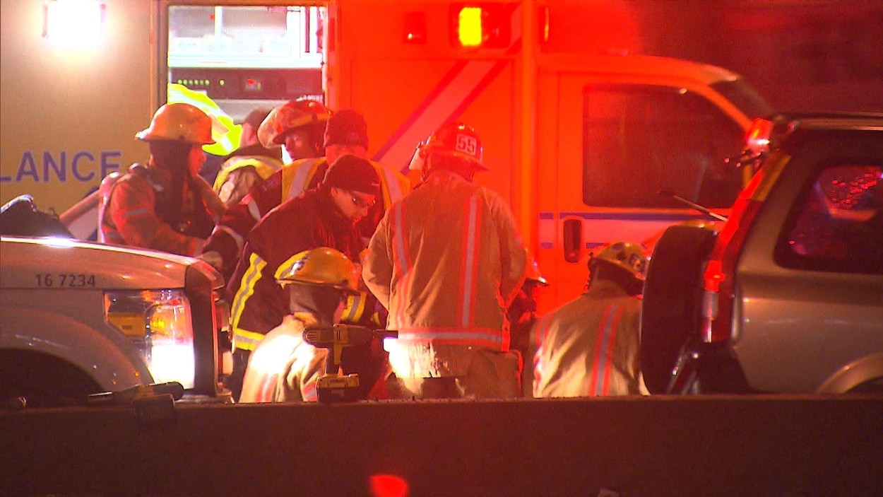 Des pompiers et des ambulanciers s'affairent devant une ambulance.