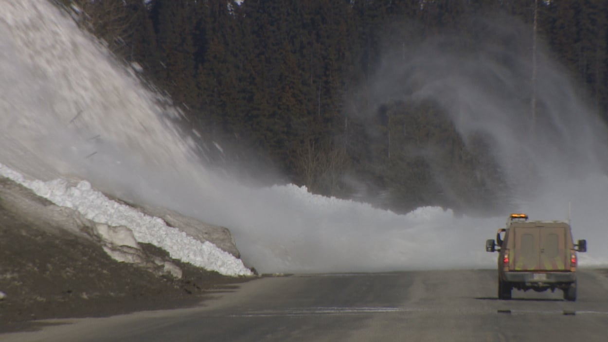 La neige finit sa trajectoire sur l'asphalte et un véhicule se tient à distance